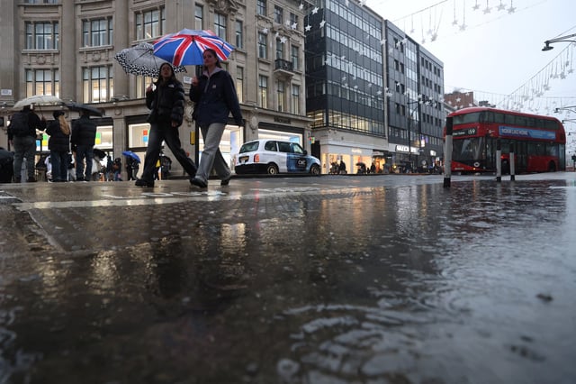 Shoppers carrying umbrellas walk past a puddle at Oxford Circus, in London, Britain, January 5, 2025. REUTERS/Hollie Adams
