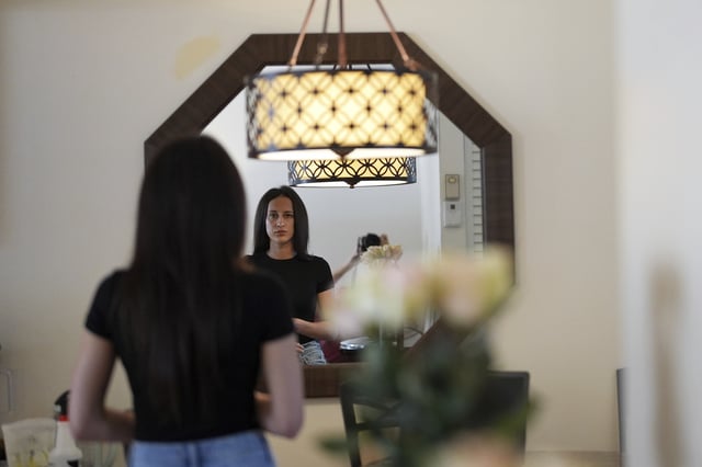 Oksana Tarasiuk looks in the mirror of the apartment she shared with her husband, Maksym Chernyak, who died in ICE custody after being held at Krome Detention Center, Tuesday, April 22, 2025, in Hallandale Beach, Fla. (AP Photo/Rebecca Blackwell)