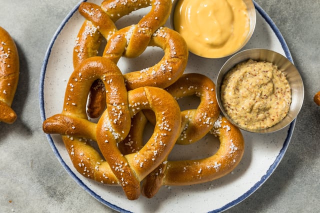 A stock image shows three homemade Bavarian soft pretzels with dip. Several pretzel retailers are offering freebies and deals for National Pretzel Day on April 26, 2025.