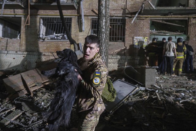 A Ukrainian serviceman carries a dog out of a house damaged by a Russian airstrike in a residential neighborhood in Kyiv, Ukraine, on Thursday, April 24, 2025. (AP Photo/Evgeniy Maloletka)