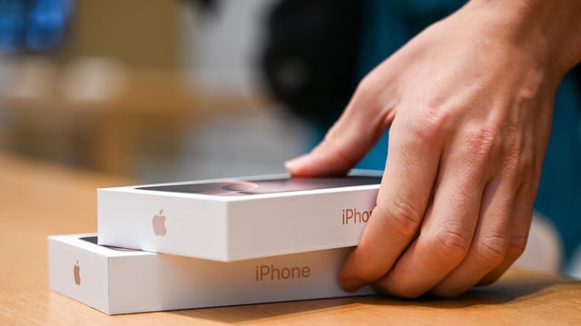 Ein Mann legt im Apple-Store zwei neue iPhones 16 auf einen Tisch. 