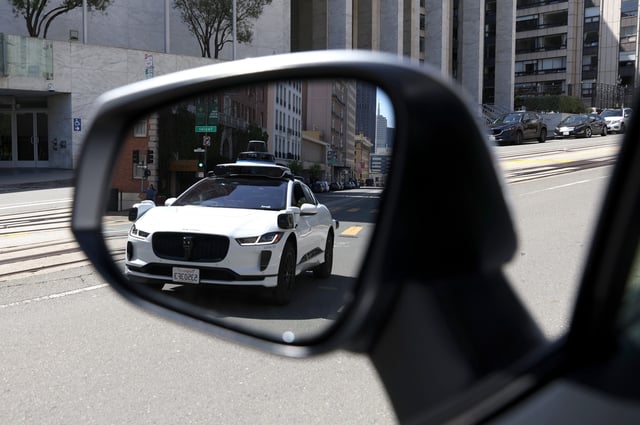 A Waymo autonomous vehicle is seen reflected in a mirror as it drives along California Street on April 11, 2022 in San Francisco, California.