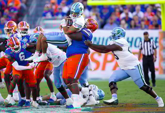 Florida Gators defensive lineman Desmond Watson (21) tackles Tulane Green Wave quarterback Ty Thompson (7). [Doug Engle/Gainesville Sun]