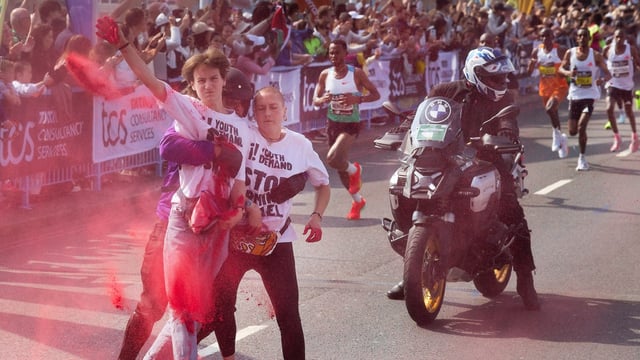 The protesters are tackled as the elite runners dodge the disruption