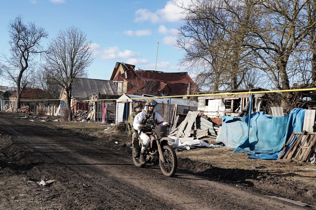 Russian soldiers ride a motorbike past destroyed houses in the village of Kazachya Loknya, which was previously held by Ukrainian troops and recently retaken by Russia's armed forces, in the Sudzha district of the Kursk region on March 18, 2025, amid the ongoing Russian-Ukrainian conflict.