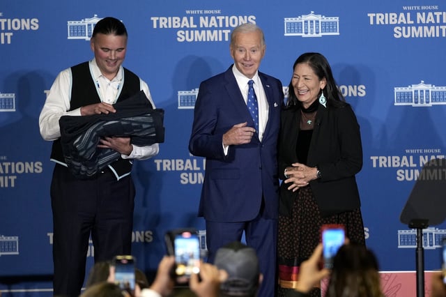 FILE - Interior Secretary Deb Haaland, right, and Bryan Newland, Assistant Secretary for Indian Affairs at the Department of the Interior, left, present President Joe Biden with an Eighth Generation blanket from a tribally-owned business, embroidered with "Joe Biden Champion for Indian Country," at the 2024 White House Tribal Nations Summit at the Department of the Interior in Washington, Dec. 9, 2024. (AP Photo/Susan Walsh, File)