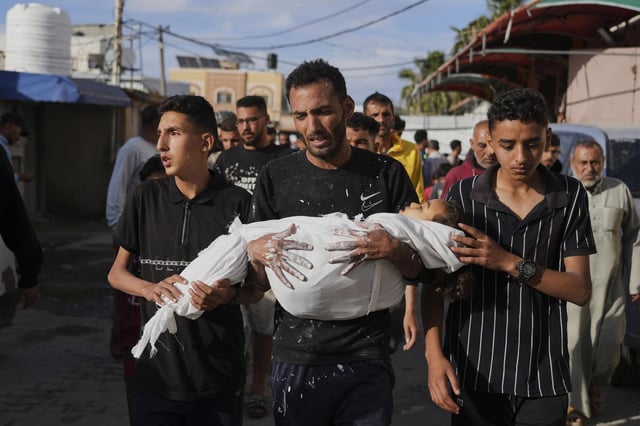 Un hombre porta el cadáver de un niño de 4 años muerto en un ataque de Israel en Deir al-Balah (Gaza), este domingo.