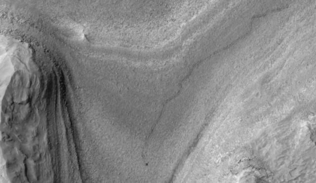 NASA’s Curiosity rover appears as a dark speck in this contrast-enhanced view captured on Feb. 28, 2025, by the HiRISE camera aboard NASA’s Mars Reconnaissance Orbiter. Trailing Curiosity are the rover’s tracks, which can linger on the Martian surface for months before being erased by the wind. NASA/JPL-Caltech/University of Arizona