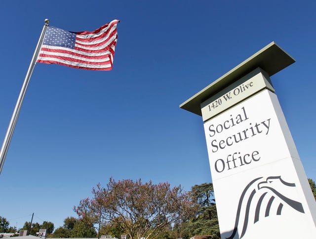 An American flag flutters in the wind next to signage for a Social Security Administration office in Burbank, California on October 25, 2012.
