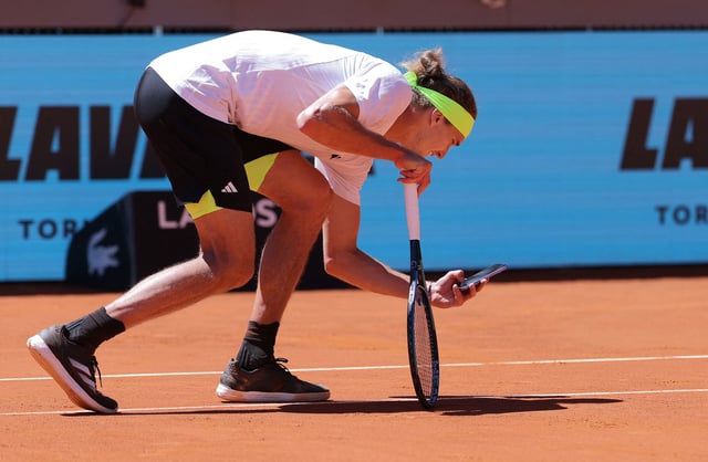 Germany's Alexander Zverev takes a picture with his mobile phone of the ball mark on the court after he disputed the referee decision during his match against Spain's Alejandro Davidovich Fokina during their 2025 ATP Tour Madrid Open tennis tournament third round singles match at the Caja Magica in Madrid, on April 27, 2025. (Photo by Thomas COEX / AFP) (Photo by THOMAS COEX/AFP via Getty Images)          