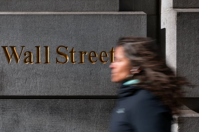 A woman walks down Wall Street in New York City, U.S., April 8, 2025. REUTERS/Kylie Cooper