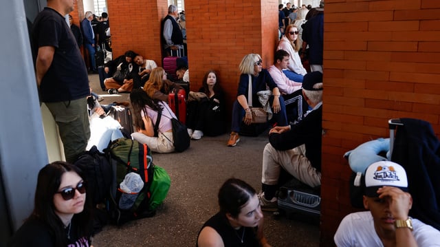 Des voyageurs sont assis à l’extérieur de la gare d’Atocha, à Madrid, ce lundi 28 avril, après sa fermeture suite à une gigantesque panne d’électricité qui paralyse le pays.