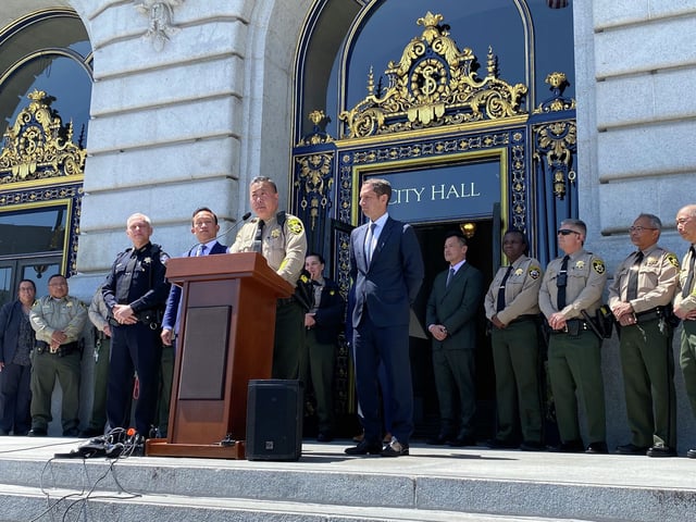 Sheriff Paul Miyamoto, center, stands next to Mayor Daniel Lurie, right. Miyamoto announced that his office will resume its ankle monitoring program following a federal court ruling. 