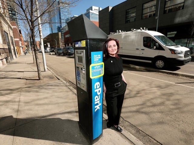 Cheryll Watson, chairwoman of the Downtown Revitalization Coalition, poses for a photo beside an EPark machine, in downtown Edmonton on Thursday, April 24, 2025. The city has started removing all physical EPark machines and is moving to a mobile app payment system. 