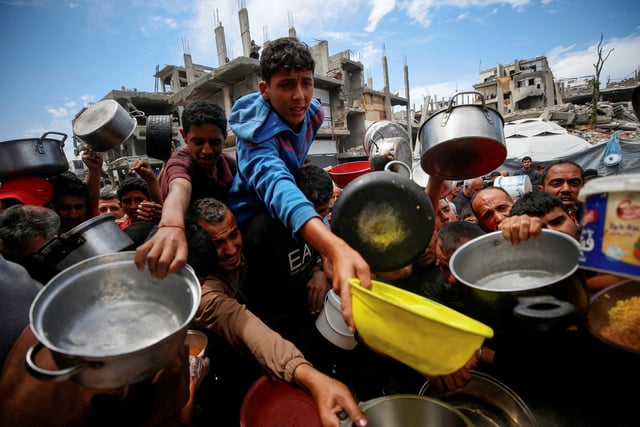 Des Palestiniens attendent de recevoir de la nourriture cuisinée par une œuvre caritative, à Beit Lahiya, dans le nord de la bande de Gaza, le 28 avril 2025.