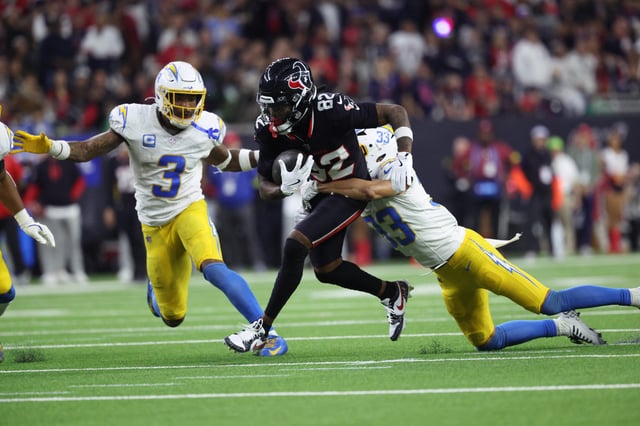 Jan 11, 2025; Houston, Texas, USA; Houston Texans wide receiver Diontae Johnson (82) runs the ball after a reception against Los Angeles Chargers defensive back Deane Leonard (33) and safety Derwin Jarnes Jr. (3) during the third quarter in an AFC wild card game at NRG Stadium. Mandatory Credit: Troy Taormina-Imagn Images/File Photo