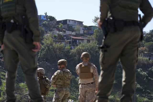 FILE - Border Patrol agents and members of the military look towards Tijuana, Mexico, as they stand between two border walls, March 21, 2025, in San Diego. (AP Photo/Gregory Bull, File)