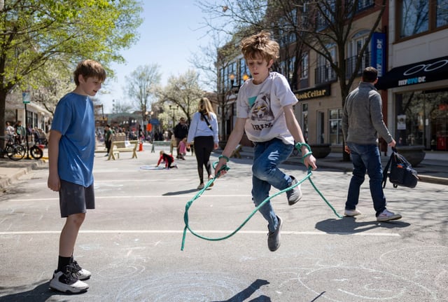 Jonah Simpson, right, 13, jumps rope alongside his brother Linus, 11, on April 27, 2025, as people enjoy the temporarily car-free space along the 4700 block of North Lincoln Avenue in Lincoln Square. (Brian Cassella/Chicago Tribune)