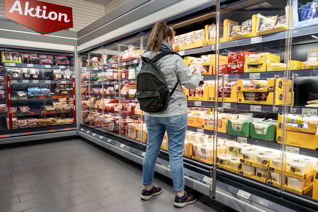 Eine Kundin betrachtet Produkte in einem Kühlregal.