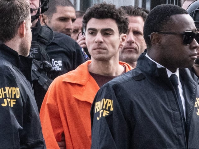 Luigi Mangione, charged in the ambush shooting murder of UnitedHealthcare CEO Brian Thompson, is escorted by law enforcement after arriving at a Manhattan heliport from Pennsylvania.