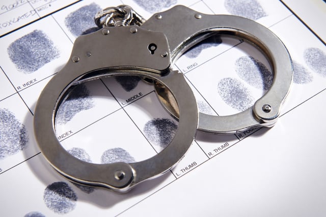 FILE - Handcuffs on top of a set of fingerprints. (J Dennis / Shutterstock)