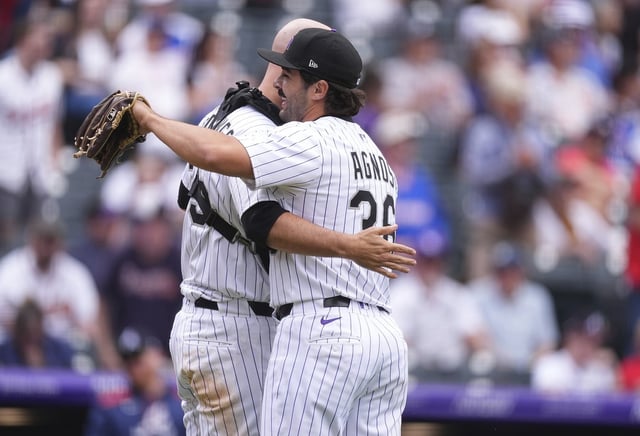 Colorado Rockies catcher Jacob Stallings, left, hugs relief pitcher Zach Agnos after he closed out the Atlanta Braves to end a baseball game, Wednesday, April 30, 2025, in Denver. (AP Photo/David Zalubowski)