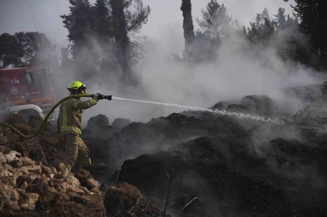 An Israeli firefighter battles a wildfire near Latrun, Israel, outside of Jerusalem, Thursday, May 1, 2025. (AP Photo/Ohad Zwigenberg)