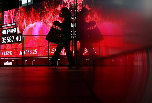 A woman walks in front of big screen displaying Japan's Nikkei share average inside a builidng in Tokyo, Japan April 25, 2025. REUTERS/Issei Kato/File photo