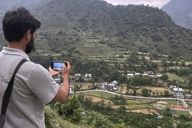 A local resident takes pictures with his mobile phone of Indian side Kashmir, at a view point from Pakistan side on the Line of Control, the de facto border dividing Pakistan and Indian Kashmir, in Chilhana, some 45 kilometres (27 miles) from Muzaffarabad, the capital of Pakistan controlled Kashmir, Thursday, May 1, 2025. (AP Photo/M.D. Mughal)