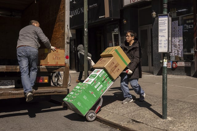 FILE - Delivery workers carry boxes outside a grocery store in the Chinatown neighborhood, Wednesday, April 9, 2025, in New York. (AP Photo/Yuki Iwamura, File)