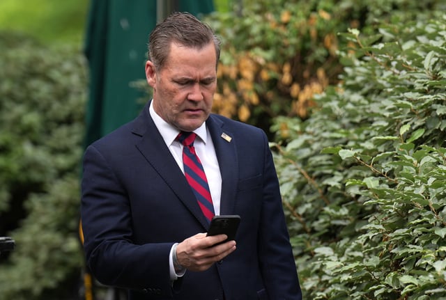 Michael Waltz looks at his phone as he prepares for a TV interview at the White House on May 01, 2025 in Washington, DC.