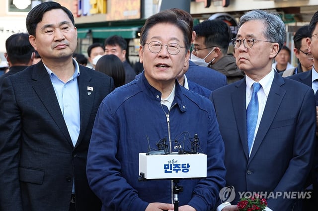 Democratic Party presidential candidate Lee Jae-myung (C) answers reporters' questions during a visit to a traditional market in Inje, 165 kilometers east of Seoul, on May 2, 2025. (Yonhap)
