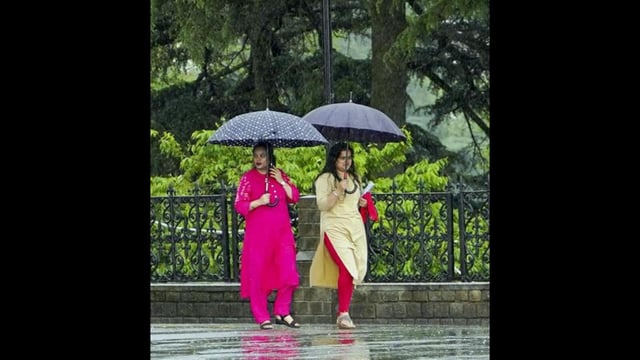 People walking in the rain on the Ridge in Shimla on Friday. Shimla and its surrounding area of Jubbarhatti were lashed by hailstorm, while several places in Himachal Pradesh received rains. (PTI Photo)