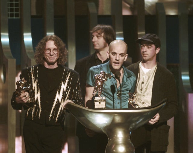 FILE - Michael Stipe, of the band R.E.M., center, speaks as he accepts the Video Vanguard award during the 1995 MTV Video Music Awards at Radio City Music Hall in New York on Sept. 7, 1995. Standing by are fellow band members, from left, Mike Mills, Peter buck and Bill Berry. (AP Photo/Bebeto Matthews, File)