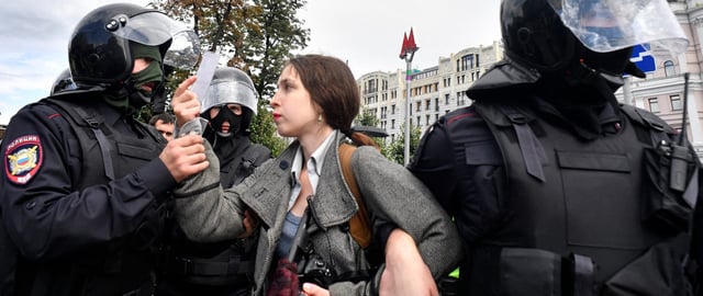 Riot police officers detain a journalist during an unsanctioned rally urging fair elections at Moscow's Pushkinskaya Square.