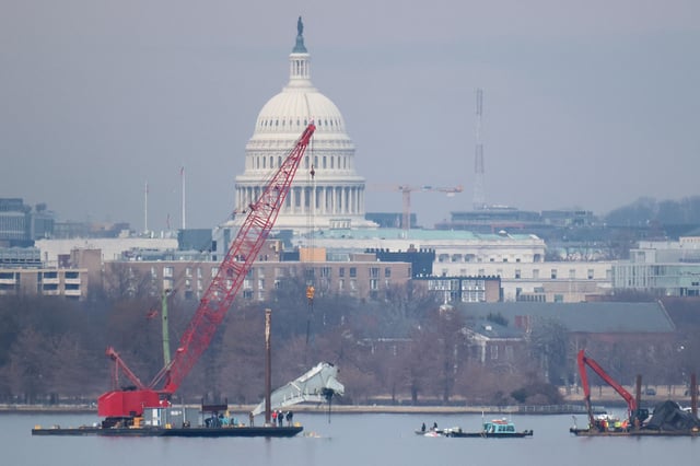 A crane lifts a piece of American Airlines flight 5342 from the Potomac River during recovery efforts on February 03, 2025 in Arlington, Virginia. An American Airlines flight from Wichita, Kansas collided midair with a military Black Hawk helicopter while on approach to Ronald Reagan Washington National Airport on January 29, 2025 outside of Washington, DC. According to reports, there were no survivors among the 67 people onboard both aircraft.