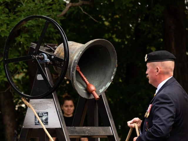 A bell is rung at the same time as a bell rings in the Netherlands during a ceremony to unveil a statue of Anne Frank at Light Horse Park in Edmonton, on Sunday, Aug. 8, 2021. The statue was installed by the Dutch Canadian Club as part of their 75th Liberation Project. 