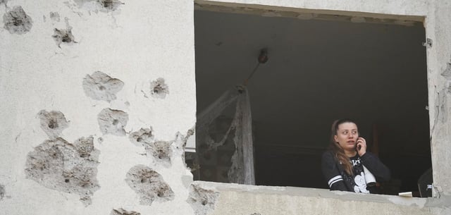 Eine Frau blickt aus dem Fenster ihrer nach einem russischen Angriff beschädigten Wohnung in Charkiw