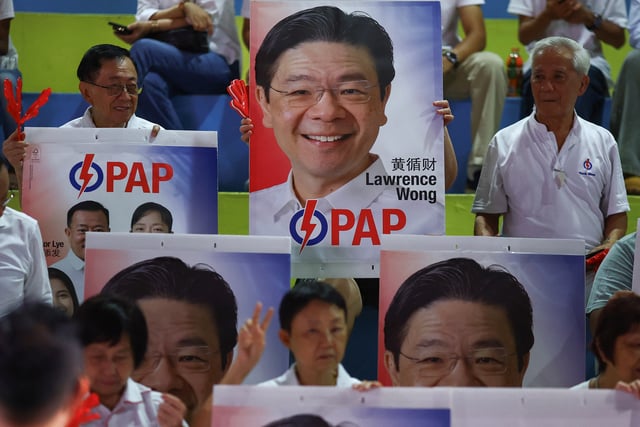People's Action Party supporters hold signs in support of Singapore's Prime Minister Lawrence Wong, as they gather at an assembly area to wait for results of the general election in Singapore, May 3, 2025. REUTERS/Edgar Su