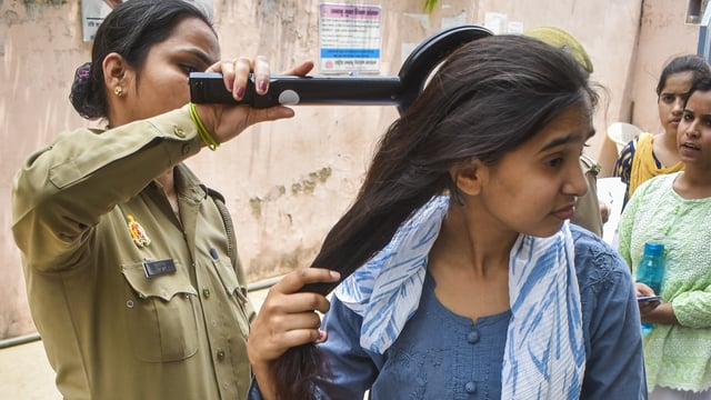 A police personnel checks an aspirant who arrived to appear for the NEET UG exam, in Meerut, Sunday, May 4, 2025. 