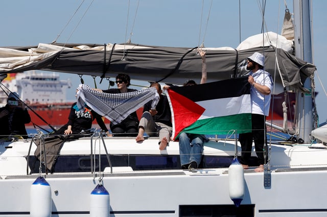 Activists hold a Palestinian flag on a yacht carrying supplies as they are prevented from approaching the damaged Gaza Freedom Flotilla vessel "Conscience", after the group said it was bombed by drones while carrying humanitarian aid to Gaza, at sea outside Maltese territorial waters, May 3, 2025. REUTERS/Darrin Zammit Lupi