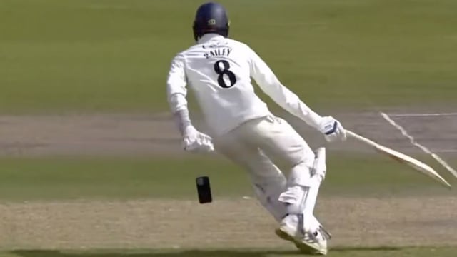 Lancashire player Tom Bailey drops his mobile phone, accidentally having carried it onto the field while preparing to bat.
