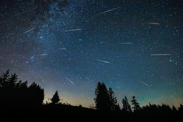 Perseid meteor shower in dark night sky with milky way above Beskydy in Czech Republic.