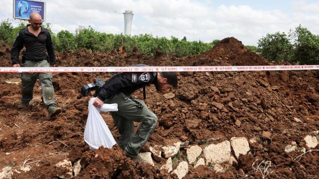 Israeli police officers investigate a crater at the site of a missile attack, launched from Yemen, near Ben Gurion Airport, in Tel Aviv, on Sunday. (REUTERS)