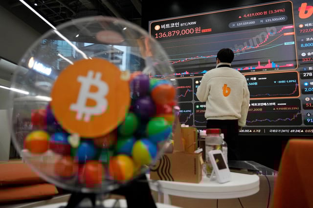 An employee watches an electronic signboard displaying the prices of Bitcoin and other cryptocurrencies at the lounge of Bithumb cryptocurrency exchange in Seoul, South Korea, in November.