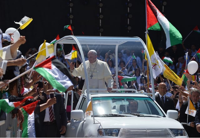 Pope Francis waves to the crowd from inside his pope-mobile as he arrives at Manger Square to celebrate an open air mass on May 25, 2014 in the West Bank Biblical town of Bethlehem.