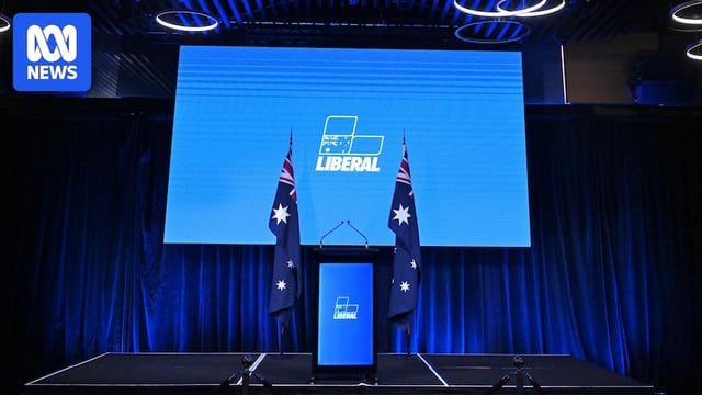 A bare stage with the liberal party logo and colours 