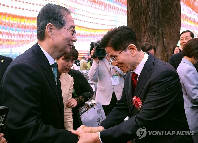 The People Power Party's (PPP) presidential candidate Kim Moon-soo (R) shakes hands with former Prime Minister Han Duck-soo as they attend a Buddha's Birthday ceremony at Jogye Temple in central Seoul on May 5, 2025. (Yonhap)