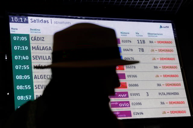 An electronic board displays information about delays as passengers wait to be given access to their trains after a cable was stolen from a high-speed train line between Madrid and Andalusia at Atocha station in Madrid, Spain, May 5, 2025. REUTERS/Susana Vera