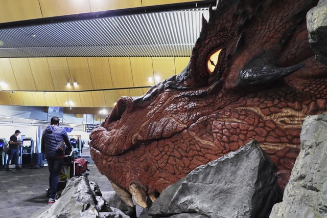 Passengers walk past a sculpture of the dragon Smaug from the Hobbit films at the check-in area at Wellington Airport in Wellington, New Zealand, Monday, May 5, 2025. (AP Photo/Charlotte Graham-McLay)